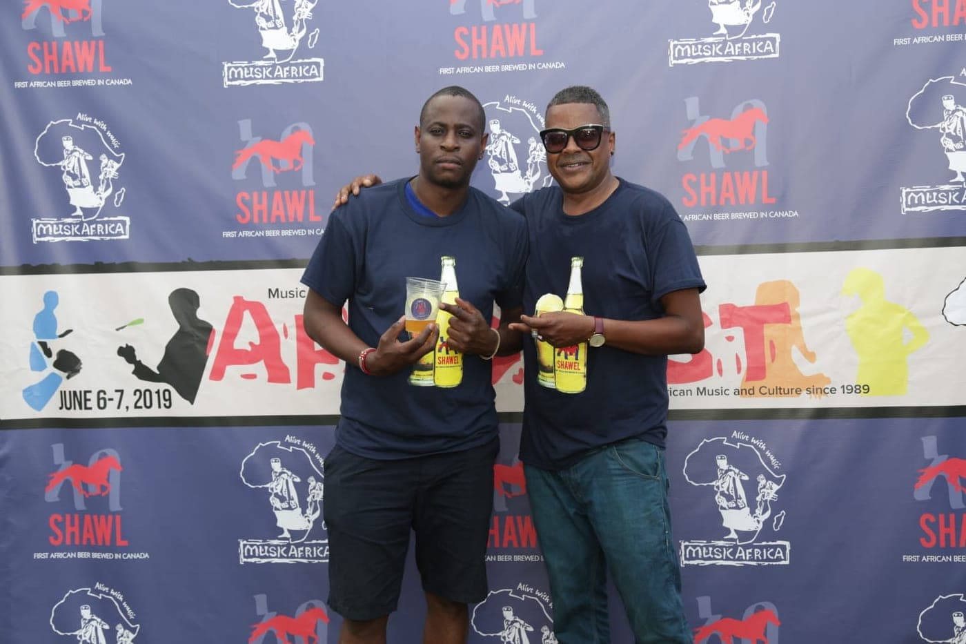 Two men presenting Shawel bottles in front of the step-and-repeat wall