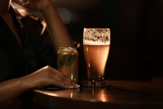 A Shawel can beside a tall glass of beer on a bar