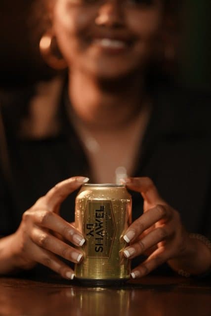 A woman smiling behind a gold Shawel can on the bar