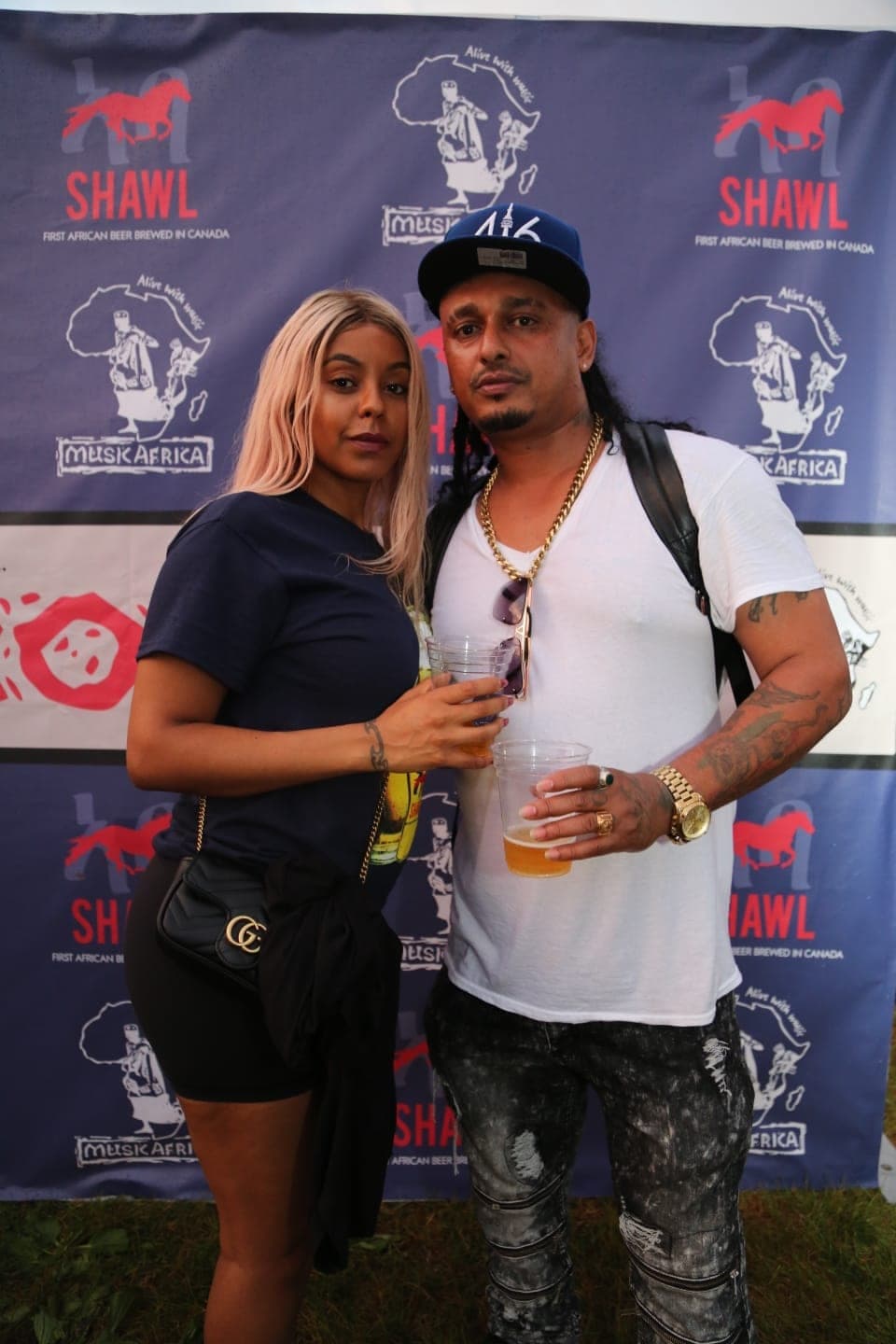 A couple with Shawel beers in front of the Shawl banner wall