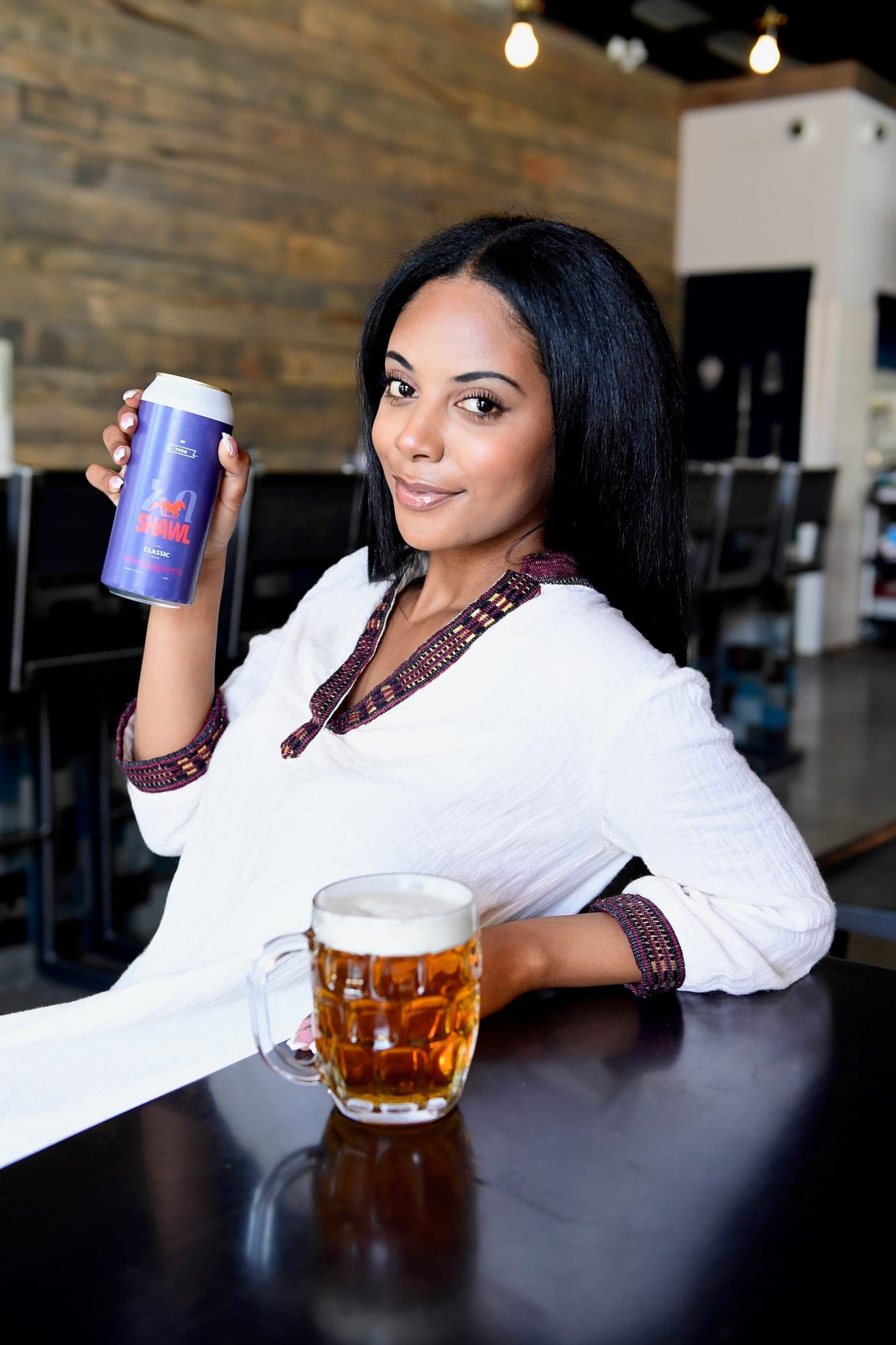 A woman in traditional dress raising a Shawel can at the bar