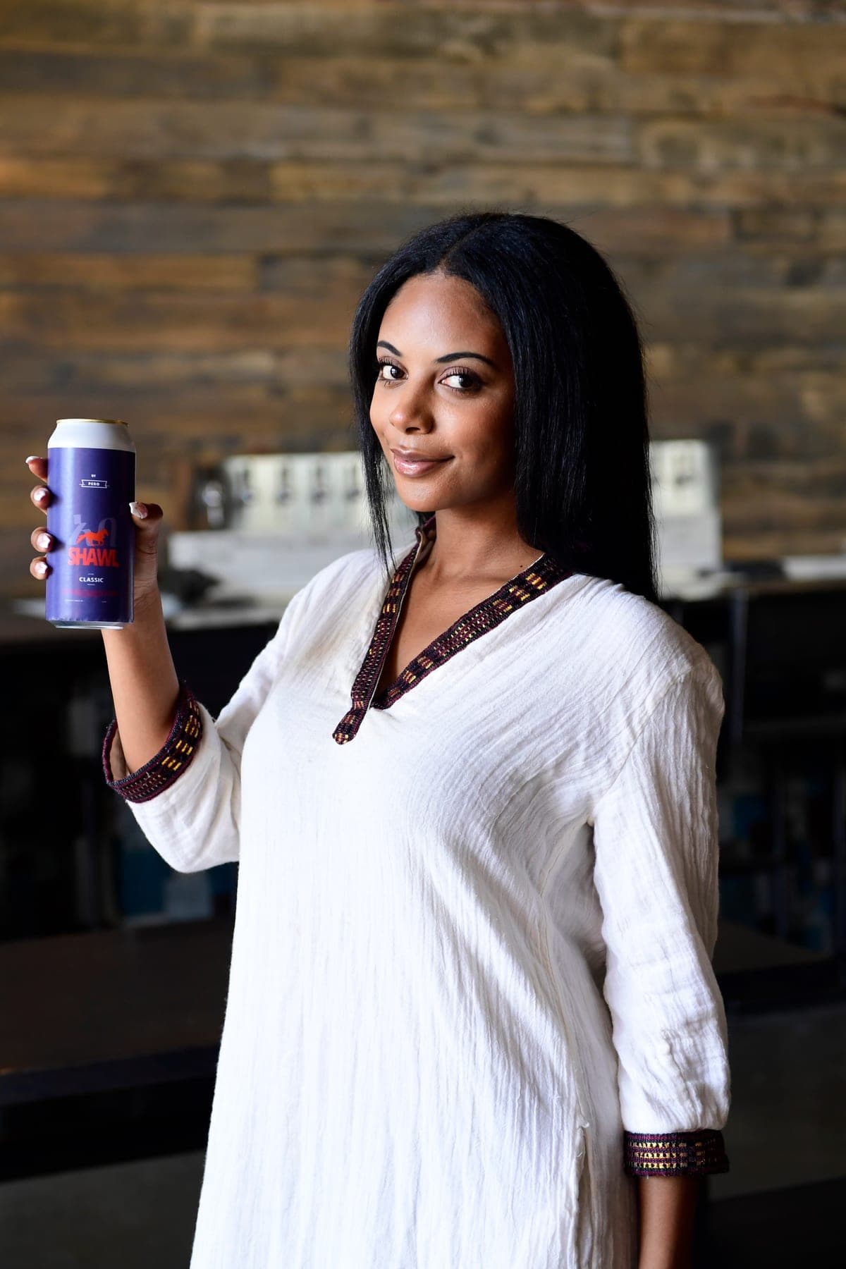 A woman standing at the bar holding a Shawel can